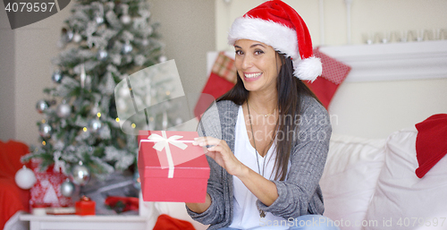Image of Excited young woman opening a Christmas gift