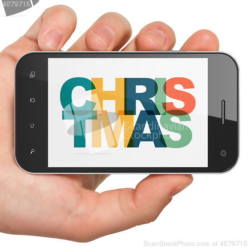 Image of Holiday concept: Hand Holding Smartphone with Christmas on  display