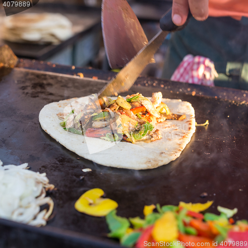 Image of Chef making chicken with grilled vegetable tortilla wrap on street stall.