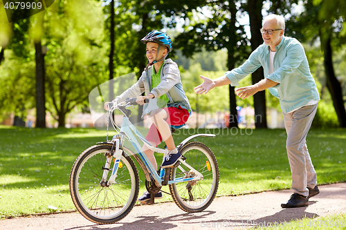 Image of grandfather and boy with bicycle at summer park