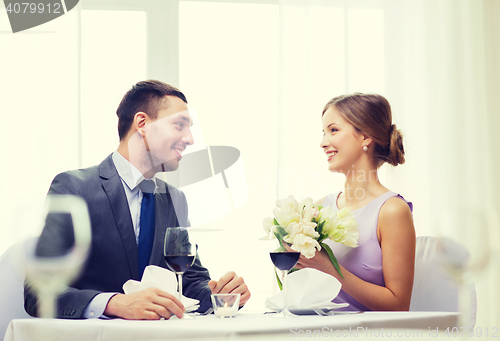 Image of smiling man giving flower bouquet at restaurant