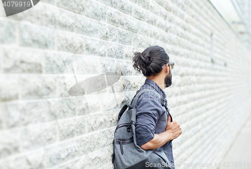 Image of man with backpack standing at city street wall