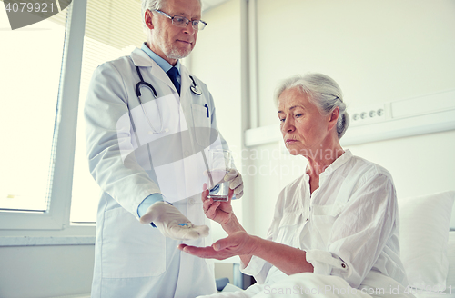 Image of doctor giving medicine to senior woman at hospital