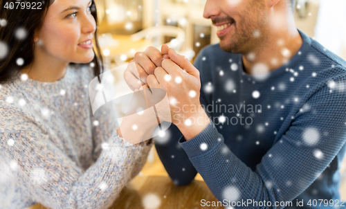 Image of happy couple holding hands at restaurant or cafe