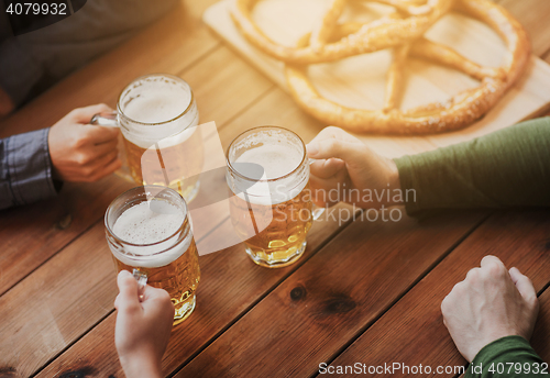 Image of close up of hands with beer mugs at bar or pub