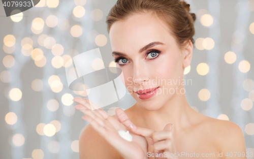 Image of woman with moisturizing cream on hand over lights