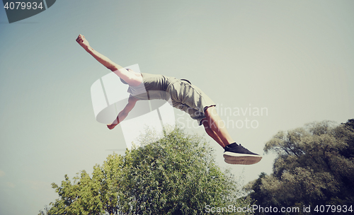 Image of sporty young man jumping in summer park