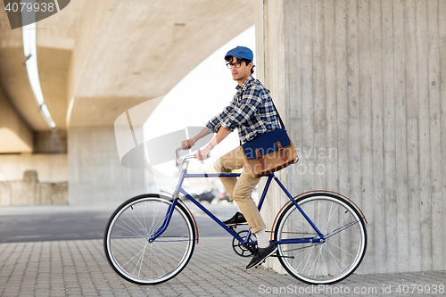 Image of young hipster man with bag riding fixed gear bike