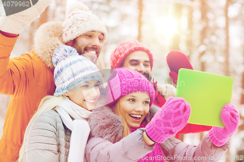 Image of smiling friends with tablet pc in winter forest