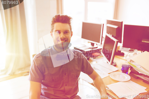 Image of happy creative male office worker with computers