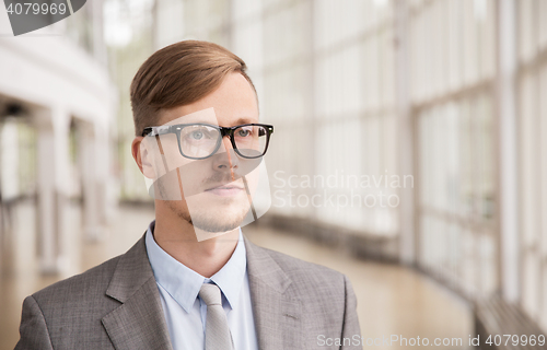 Image of young businessman in suit and glasses at office