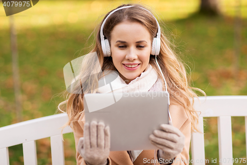 Image of woman with tablet pc and headphones in autumn park
