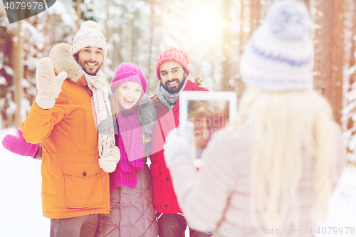 Image of smiling friends with tablet pc in winter forest