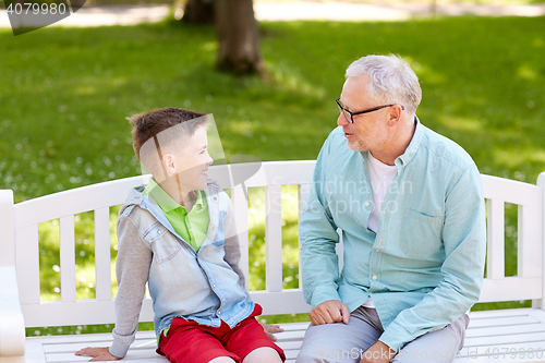 Image of grandfather and grandson talking at summer park