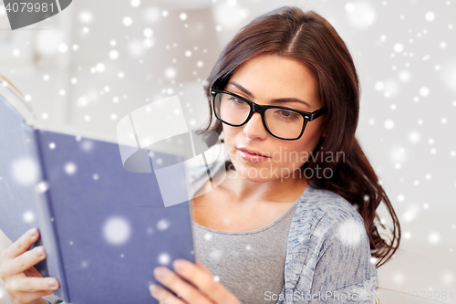 Image of young woman in glasses reading book at home