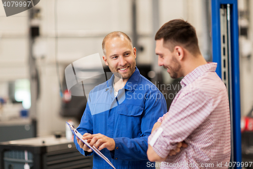 Image of auto mechanic with clipboard and man at car shop