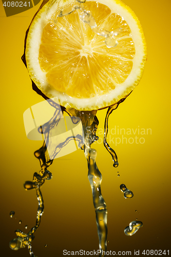 Image of Lemon juice pouring down from half of  isolated on orange background