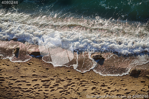 Image of Waves lapping on the sandy beach and footprints