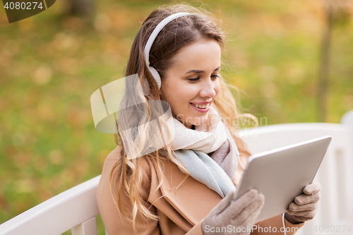 Image of woman with tablet pc and headphones in autumn park