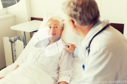 Image of doctor visiting senior woman at hospital ward