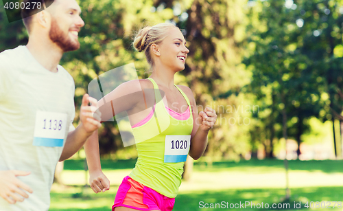 Image of happy sportsmen couple racing wit badge numbers