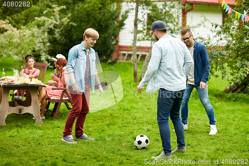 Image of happy friends playing football at summer garden