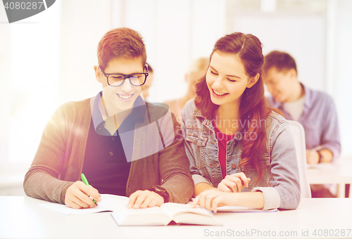 Image of two teenagers with notebooks and book at school