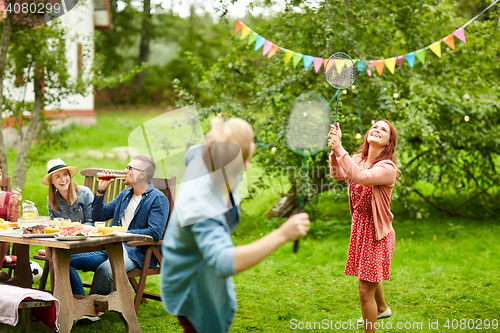 Image of happy friends playing badminton at summer garden