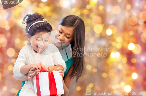 Image of happy mother and girl with gift box over lights