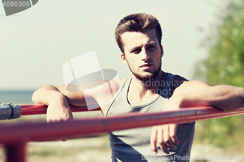 Image of young man exercising on parallel bars outdoors