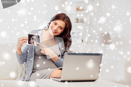 Image of pregnant woman with ultrasound image and laptop