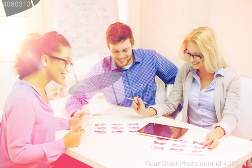 Image of smiling team with table pc and papers working