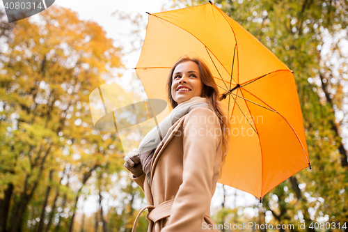 Image of happy woman with umbrella walking in autumn park