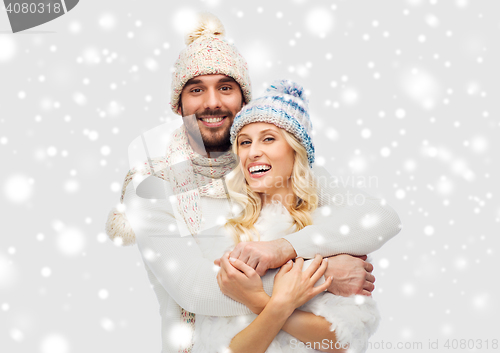 Image of smiling couple in winter clothes hugging over snow
