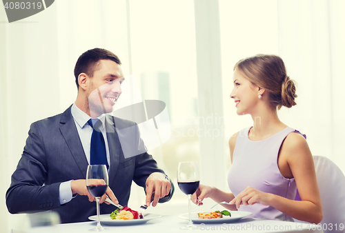 Image of smiling couple eating main course at restaurant