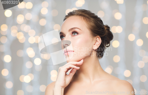 Image of beautiful woman touching her face over lights