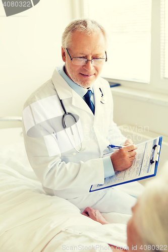 Image of senior woman and doctor with clipboard at hospital