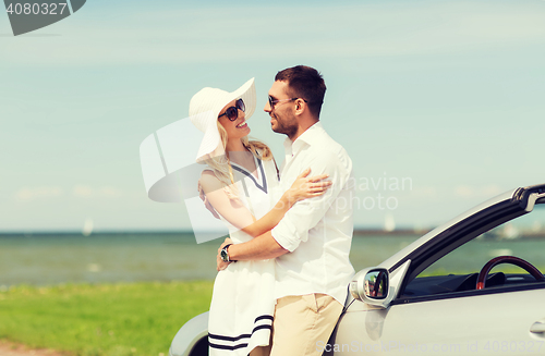 Image of happy man and woman hugging near car at sea