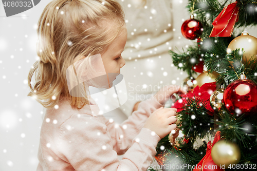 Image of little girl decorating christmas tree at home