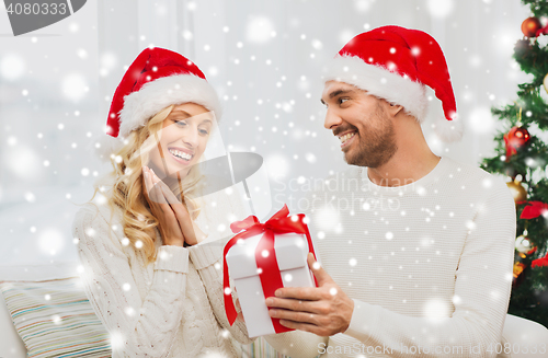 Image of happy couple at home with christmas gift box