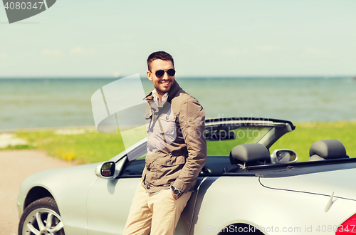 Image of happy man near cabriolet car outdoors