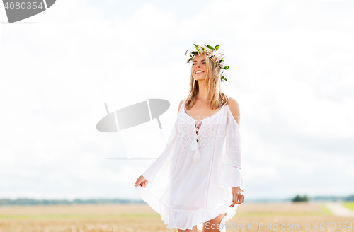 Image of happy young woman in flower wreath on cereal field