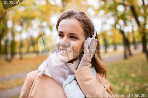 Image of woman in headphones listening music at autumn park