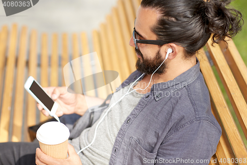 Image of man with earphones and smartphone drinking coffee