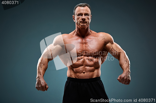 Image of torso of attractive male body builder on gray background.