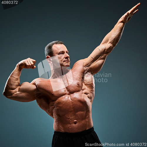 Image of torso of attractive male body builder on gray background.