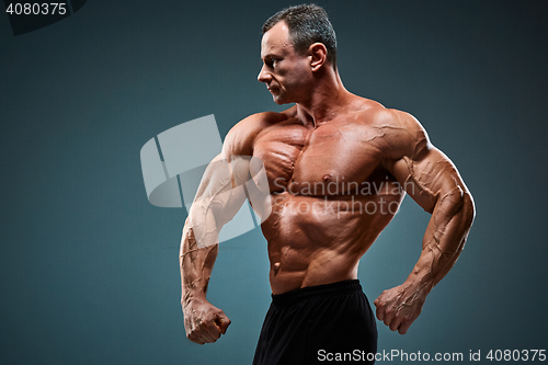 Image of torso of attractive male body builder on gray background.