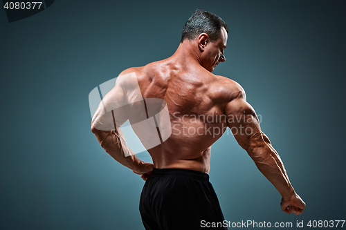 Image of torso of attractive male body builder on gray background.