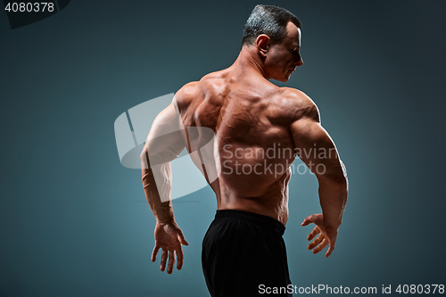 Image of torso of attractive male body builder on gray background.