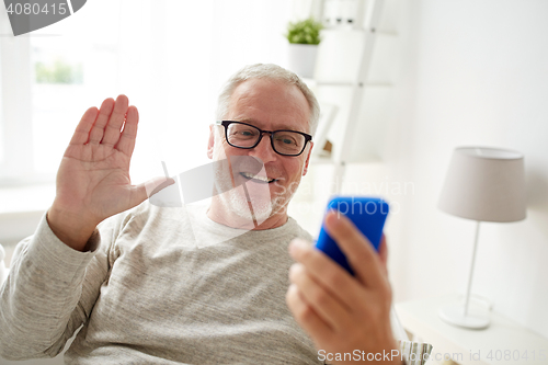 Image of senior man having video call on smartphone at home